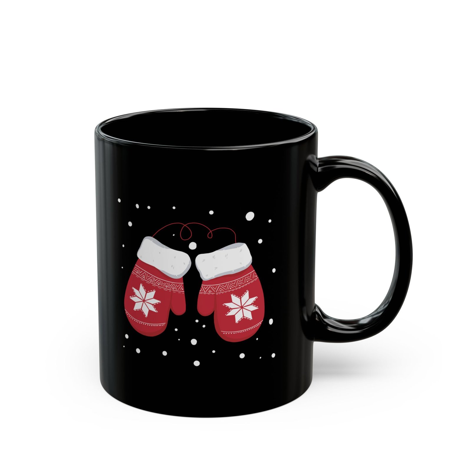 Black ceramic mug with red snowflake mittens in falling snow