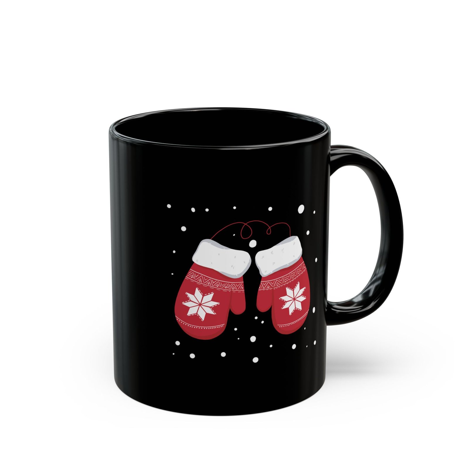 Black ceramic mug with red snowflake mittens in falling snow
